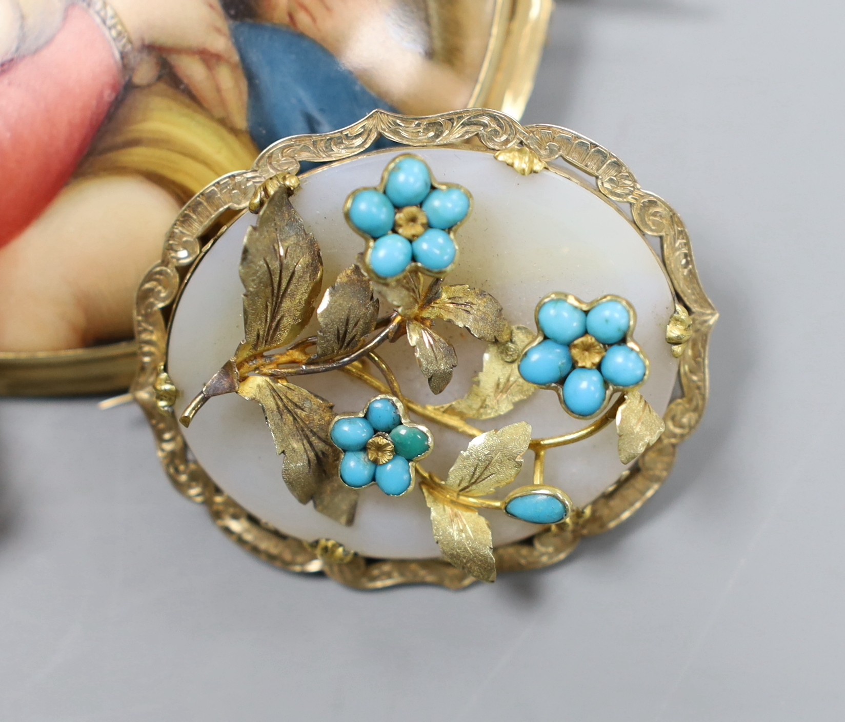 A Victorian 15ct gold mounted porcelain plaque, decorated with the Madonna della Sedia, 8cm, a Swiss landscape enamel brooch with 15ct mount, 6.5cm and a Pinchbeck brooch with turquoise set foliate decoration